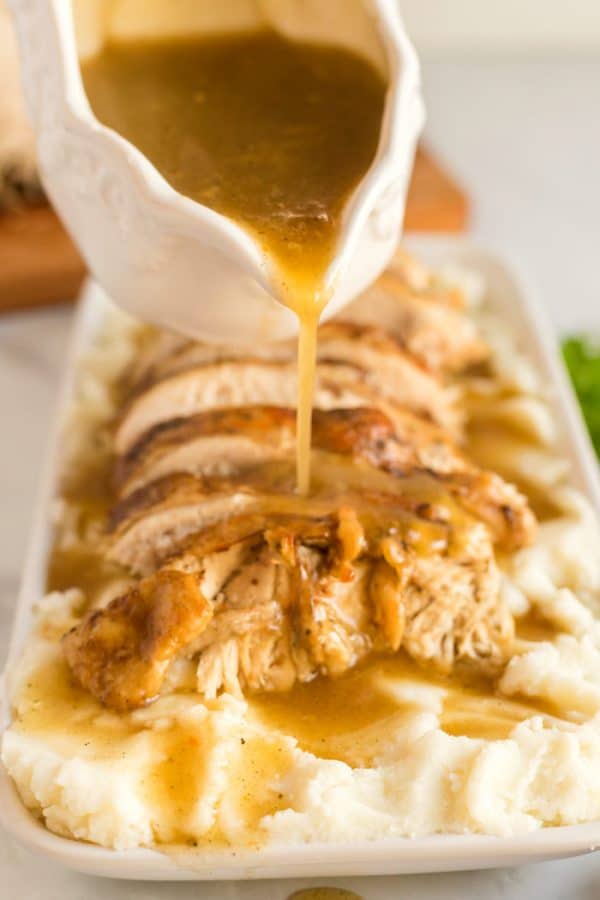 Gravy being poured over mashed potatoes.
