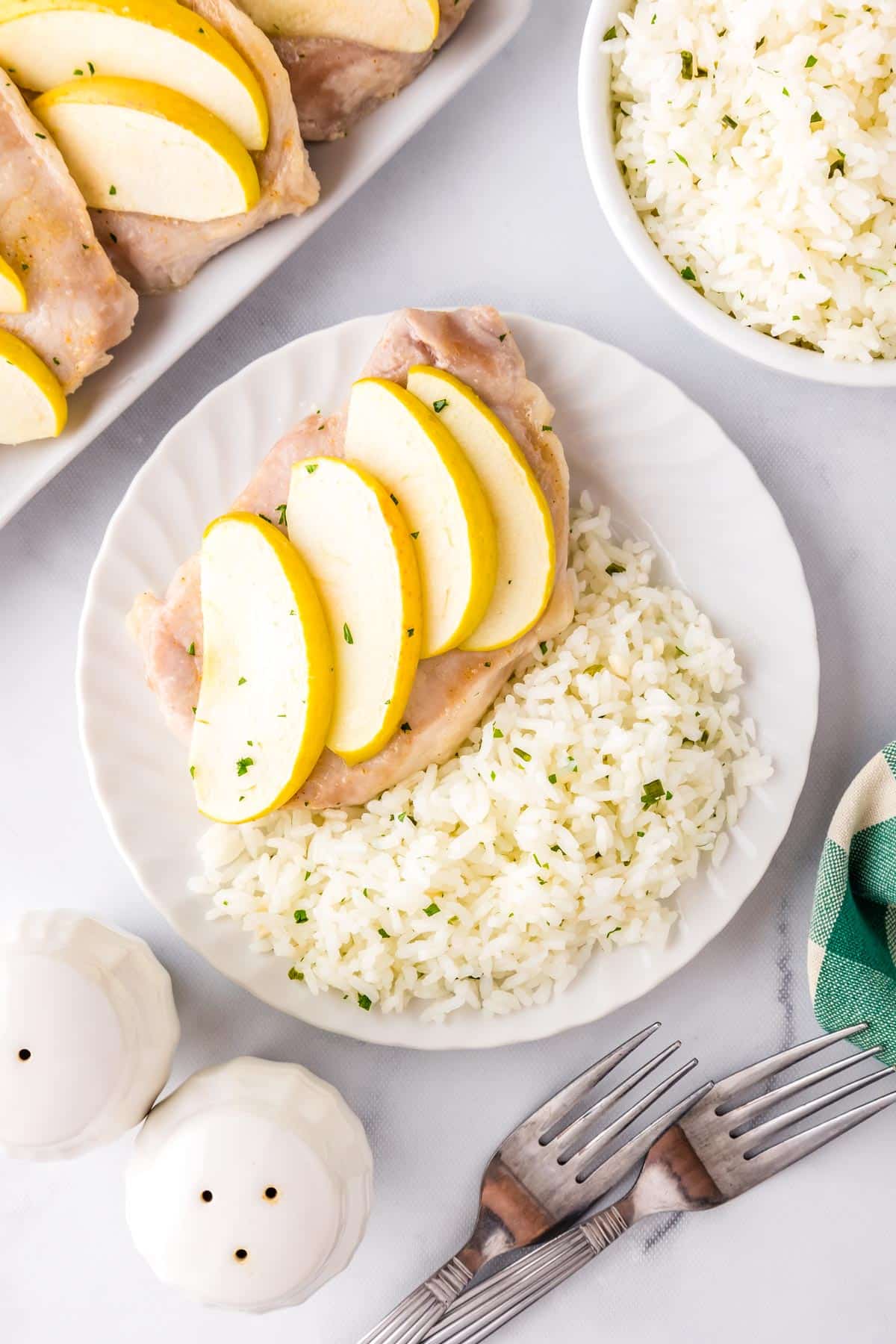 Oven pork chops with apples on a plate with some rice.