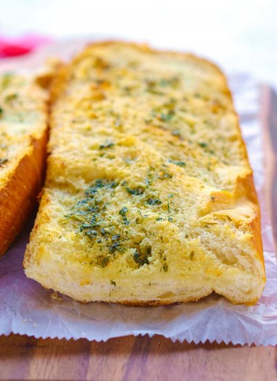 Baked garlic bread on a wooden cutting board.