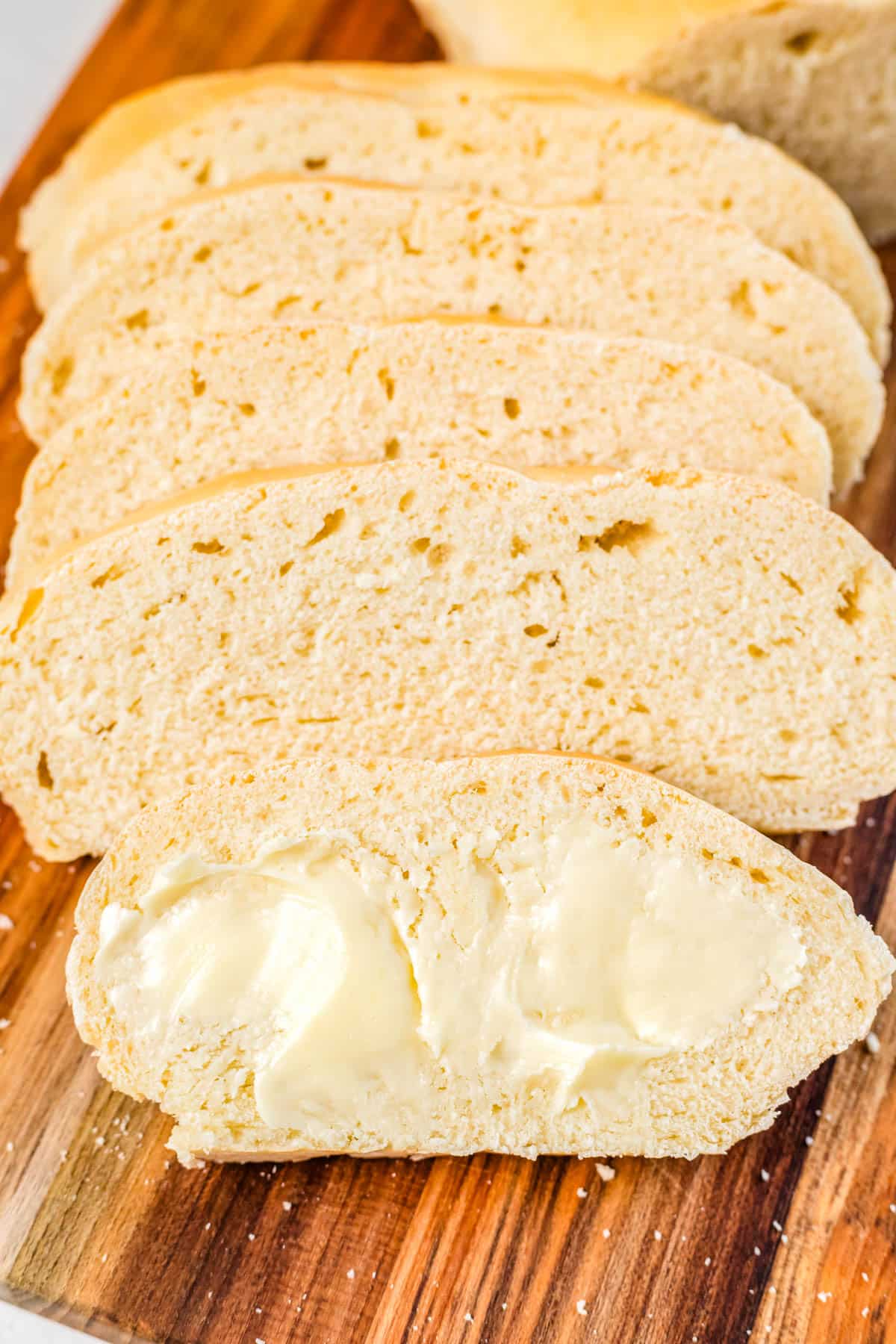 Alices of 1 hour bread on a cutting board and 1 slice is buttered.