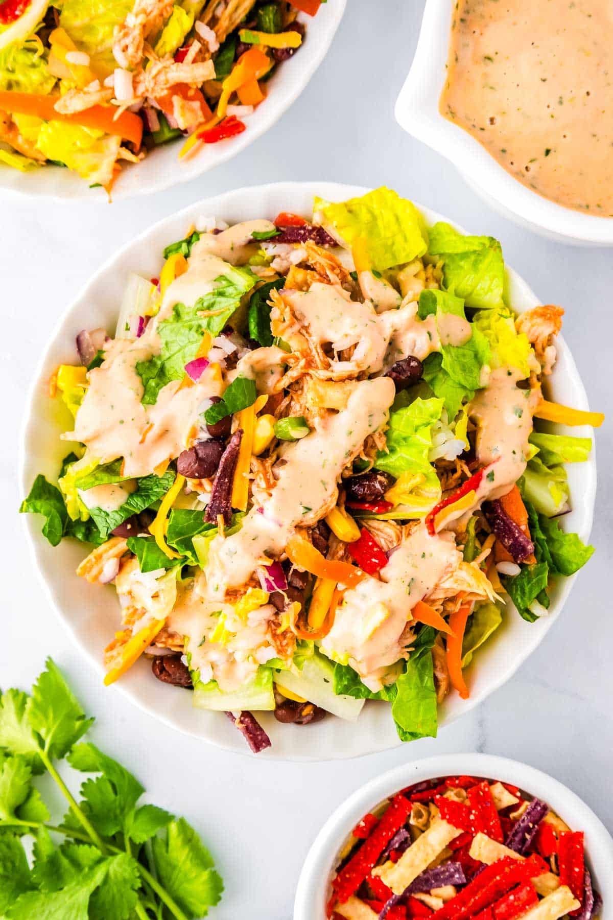 A serving of salad in a white bowl with a drizzle of dressing.
