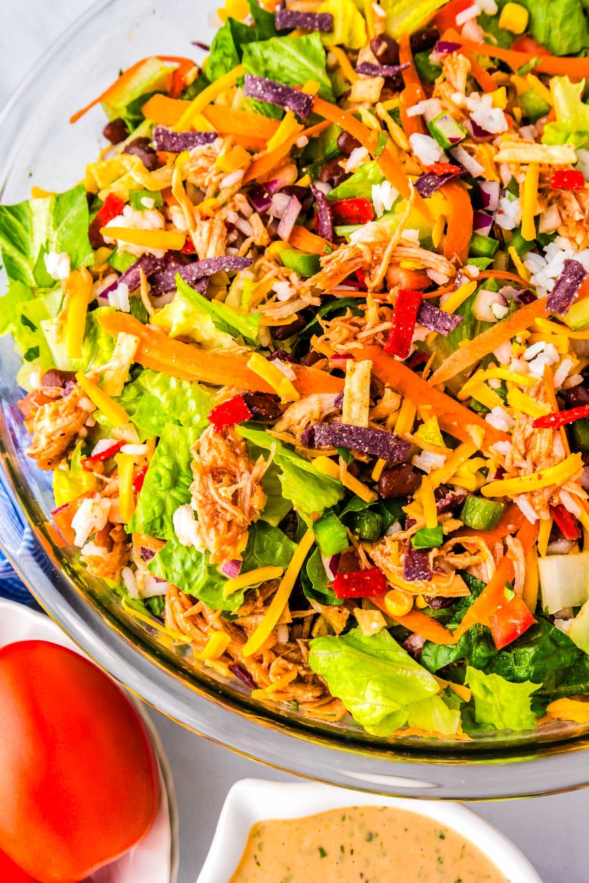 A salad with onion, pepper, rice, tomatoes, black beans, cheese, tortilla strips, and BBQ ranch dressing.