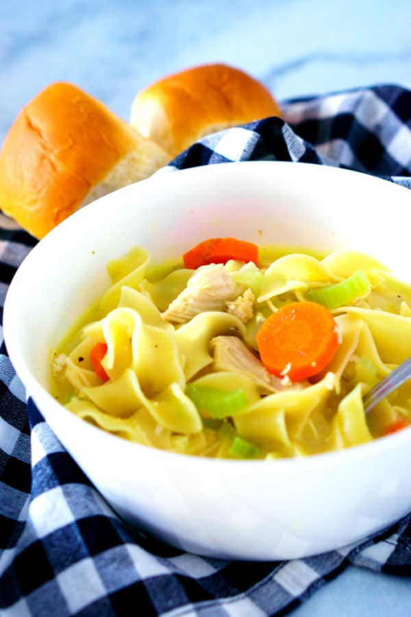 Side shot of slightly creamy chicken noodle soup in a serving bowl.