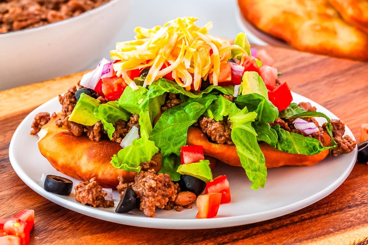 Two finished fry bread tacos on a with plate.