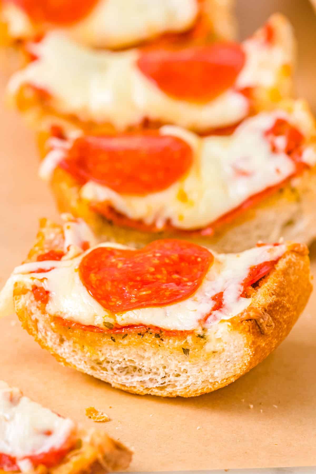 A close up of a slice of Homemade French Bread Pizza on a cutting board.