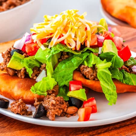A close up of two Fry Bread Tacos on a white plate.