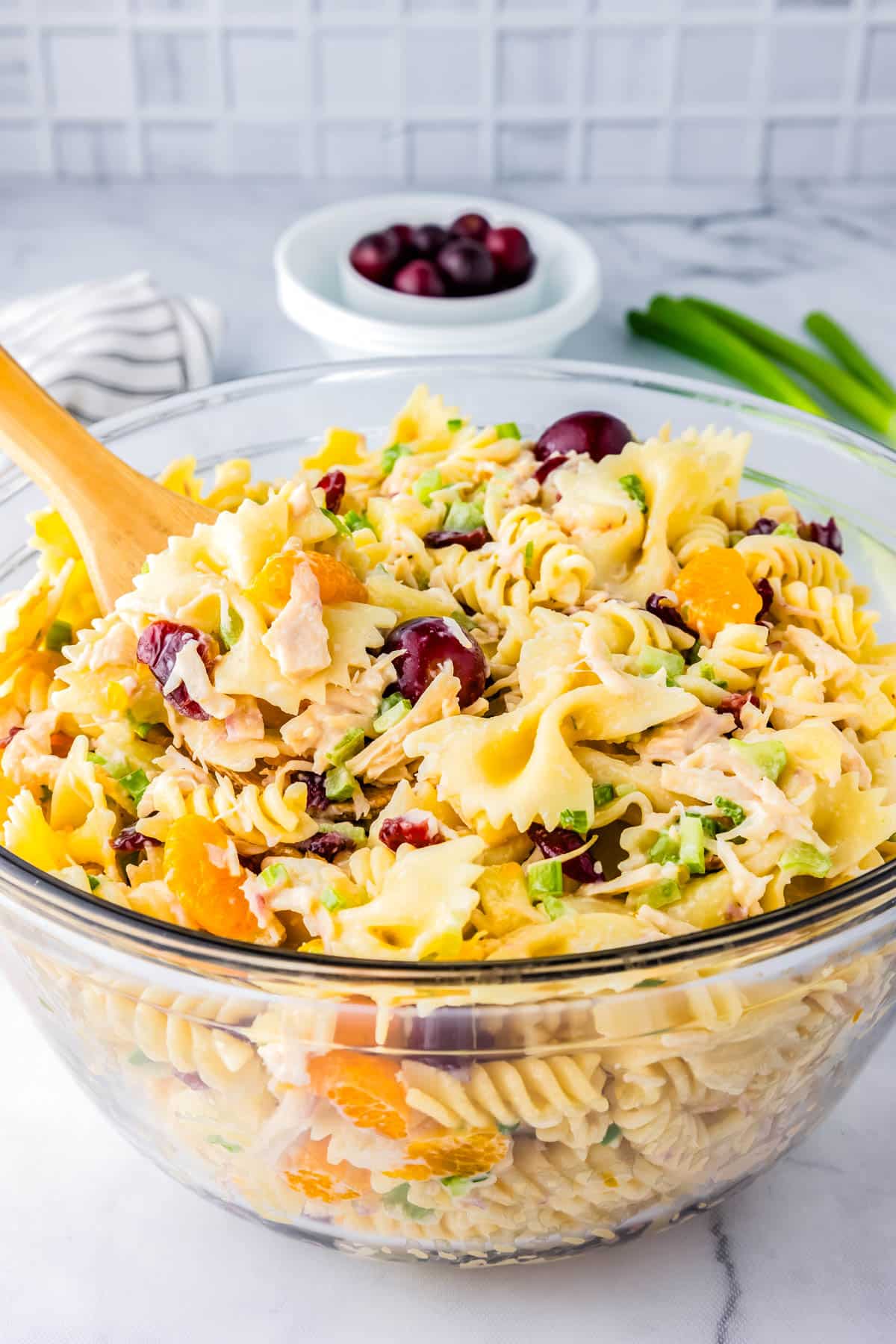 Pasta salad with chicken in a clear glass serving bowl.