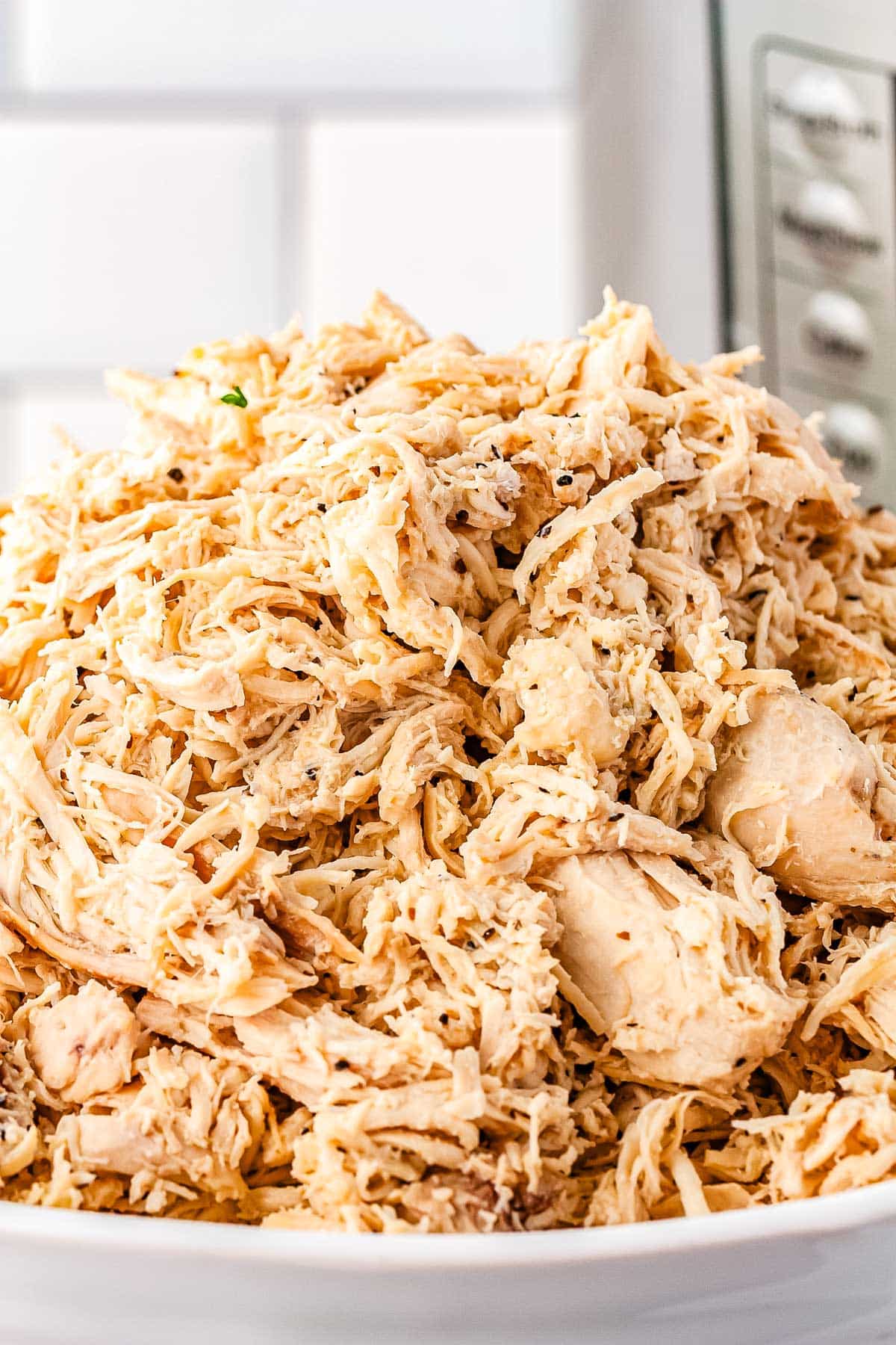 A close up of a heapping bowl full of shredded chicken.