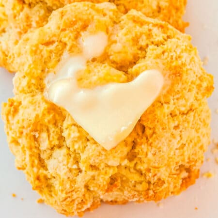 A close up of a biscuit with some butter on it that is slightly melted.