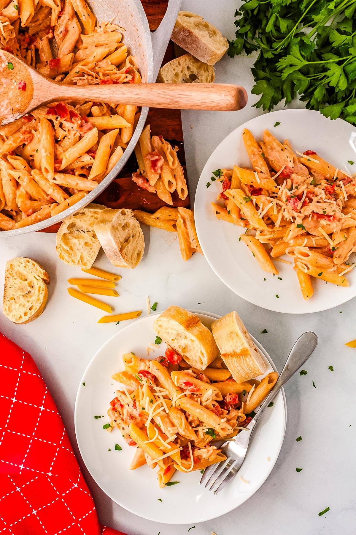 An overhead picture of the finished Tomato Chicken Alfredo on plates and in a pasta pot.