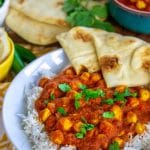 Overhead view of chana masala on a white plate with naan.