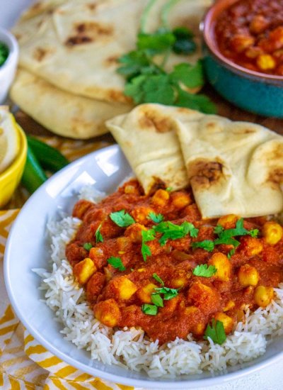 Overhead view of chana masala on a white plate with naan.