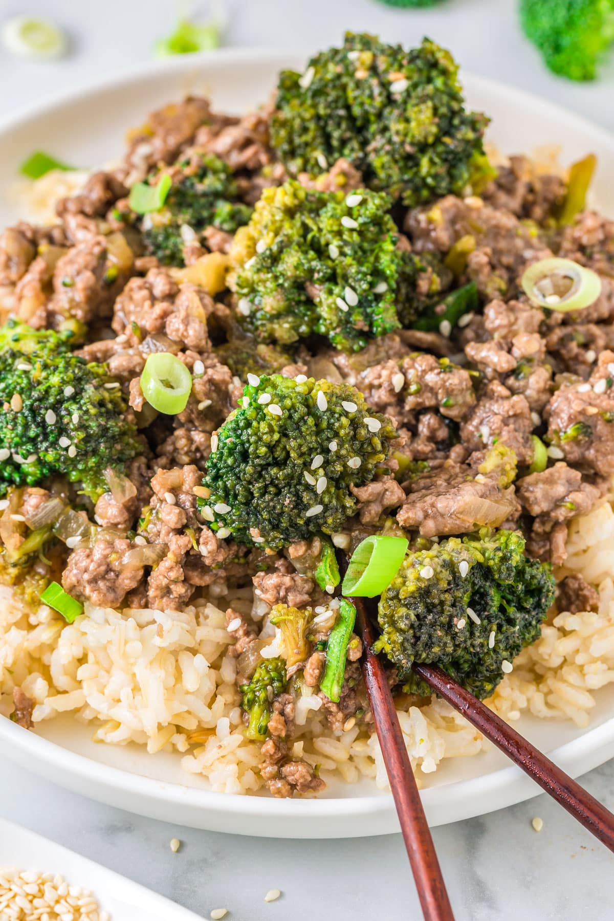 A close up of the finished Ground Beef and Broccoli served over rice in a white bowl. 