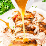 a gravy boat pouring gravy over turkey slices
