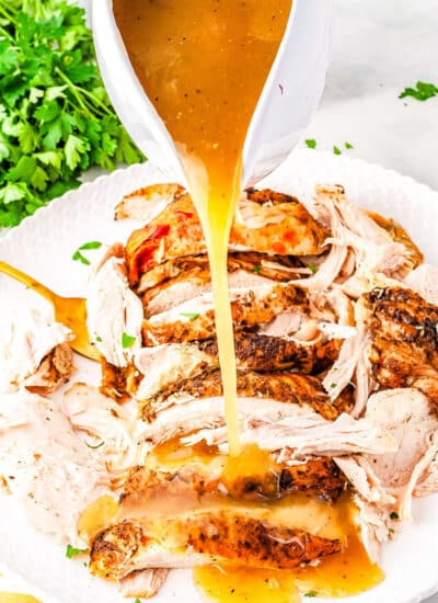 a gravy boat pouring gravy over turkey slices