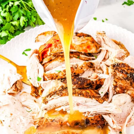 a gravy boat pouring gravy over turkey slices