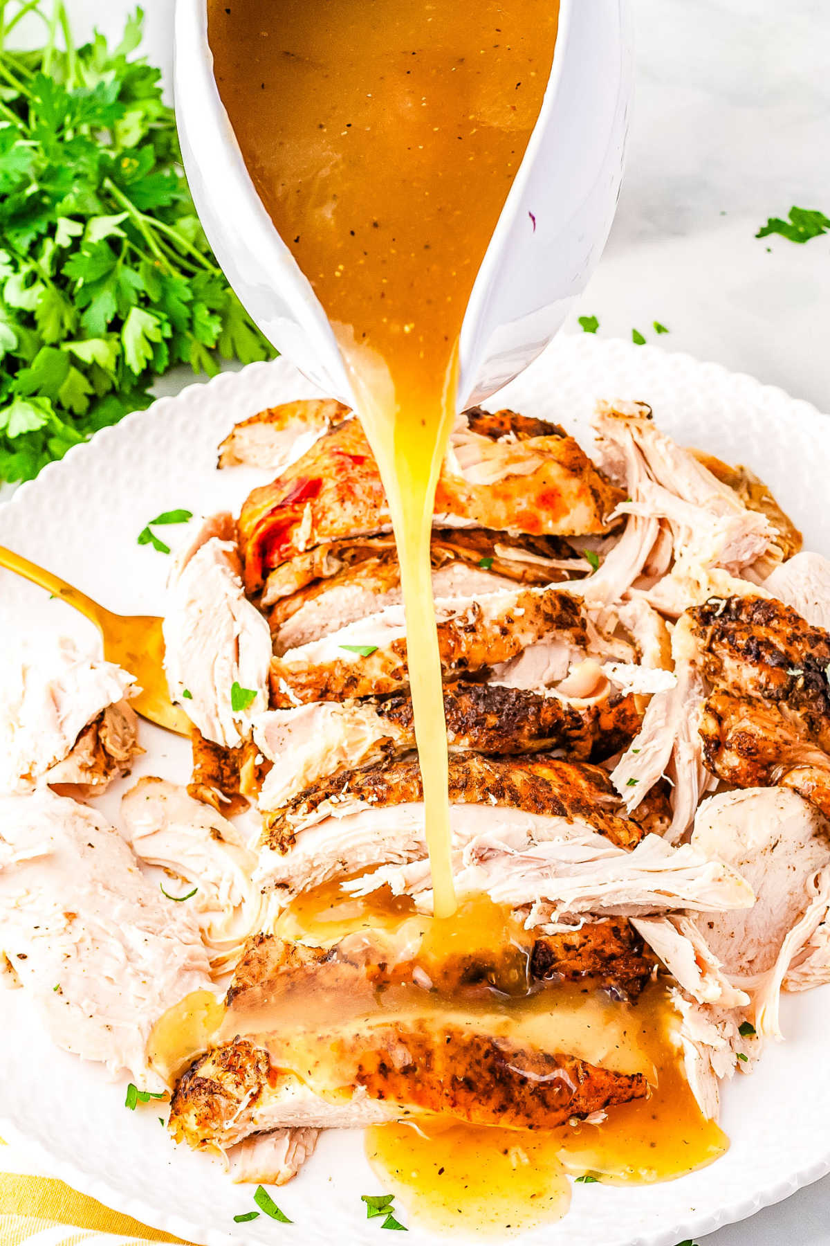 a gravy boat pouring gravy over turkey slices