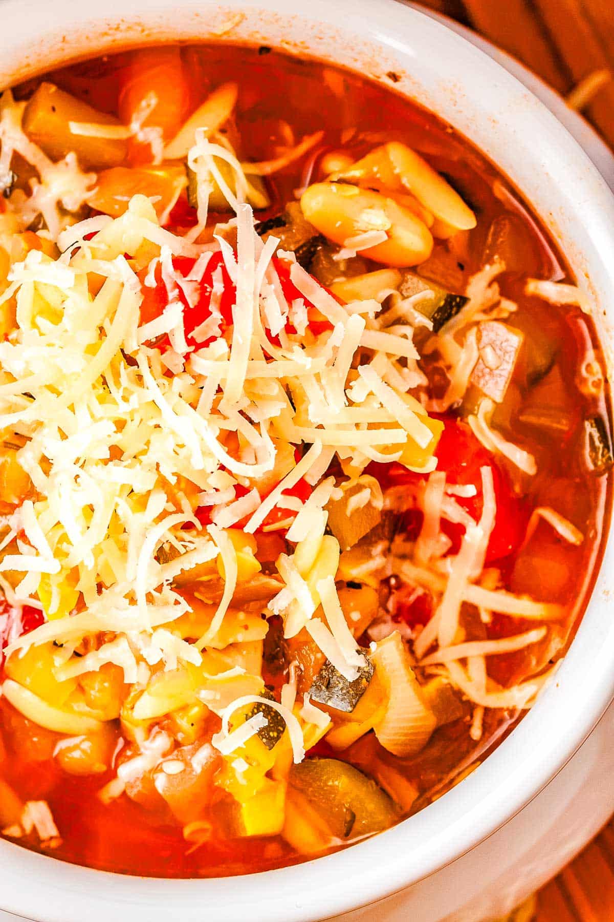 Soup in a white bowl topped with shredded Parmesan cheese.