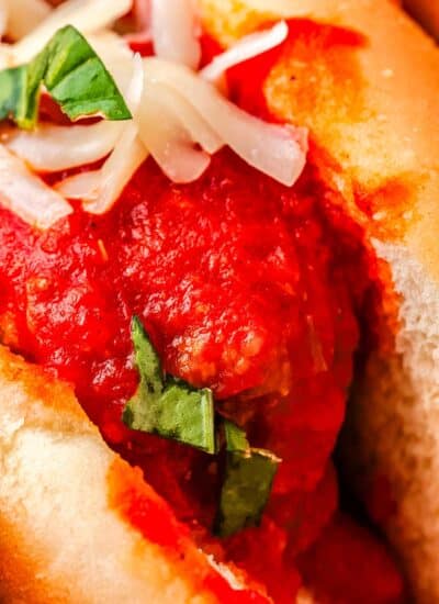 A close up of a saucy meatball in a toasted grinder roll.
