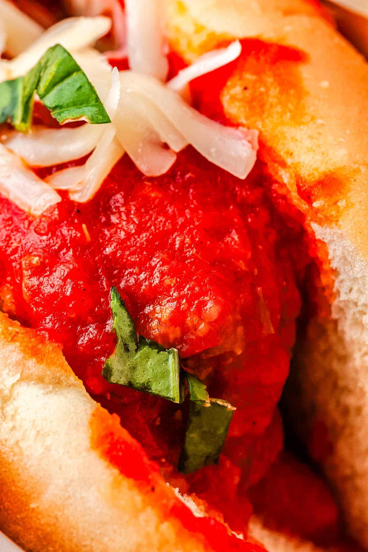 A close up of a saucy meatball in a toasted grinder roll.