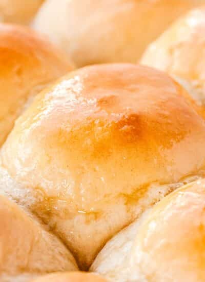 A close up picture of the dinner rolls in a pan and glistening with melted butter.