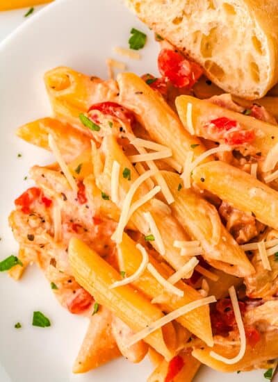 Some fo the tomato alfredo sauce over pasta on a white plate.