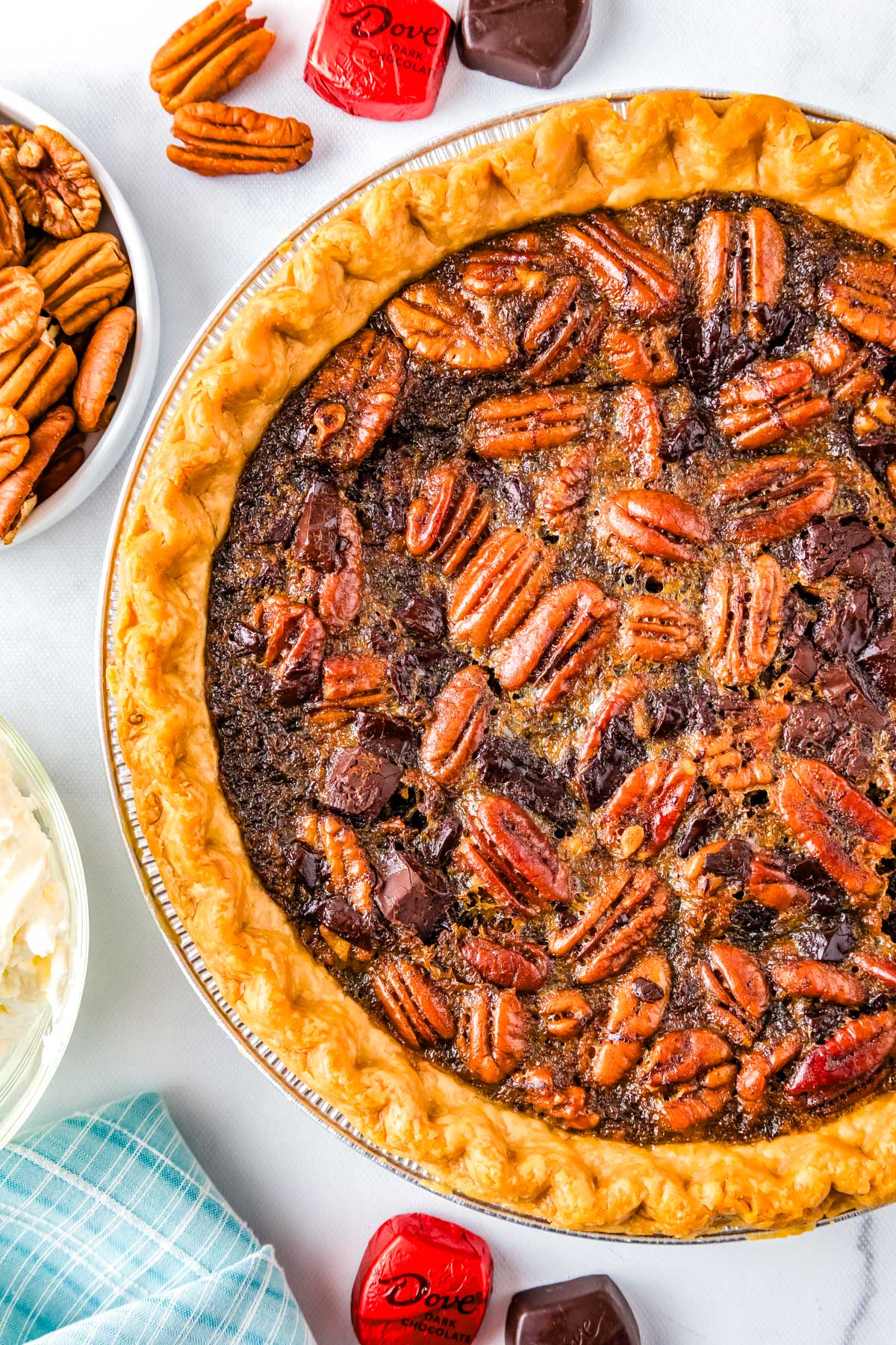 The finished Dark Chocolate Pecan Pie with pecans and dark chocolate surrounding the pie. 