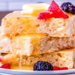 Three pancakes stacked with syrup and fruit.
