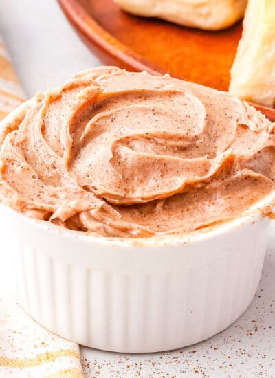 cinnamon honey butter in a white butter dish with a roll in the background