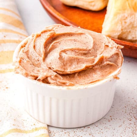 cinnamon honey butter in a white butter dish with a roll in the background