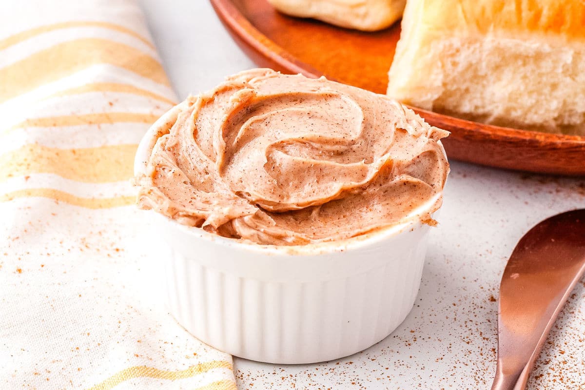 cinnamon honey butter in a white butter dish with a roll in the background