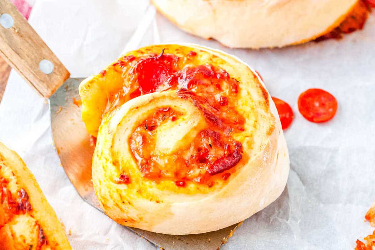 a close up of a pepperoni pizza wheel on a spatula