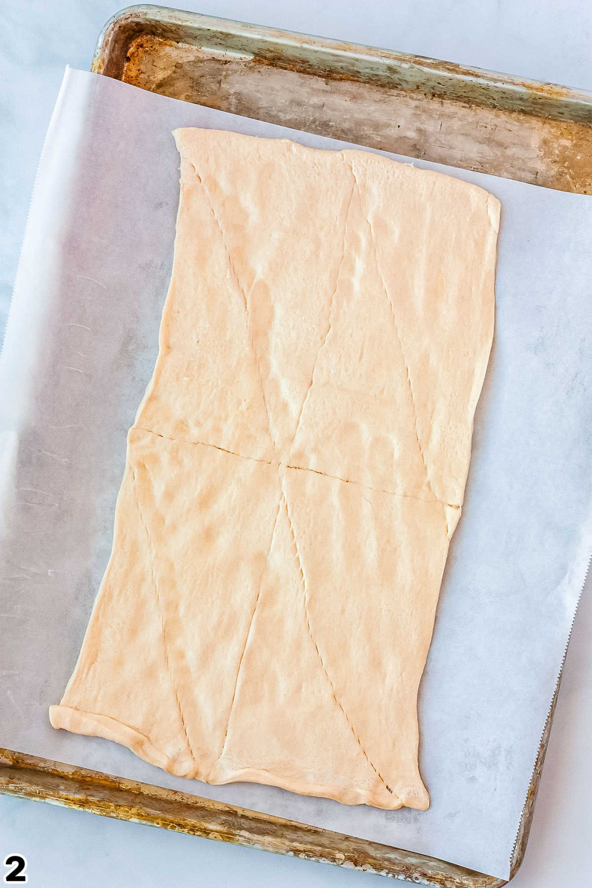Crescent Rols rolled out and the seams pressed together on a baking sheet.
