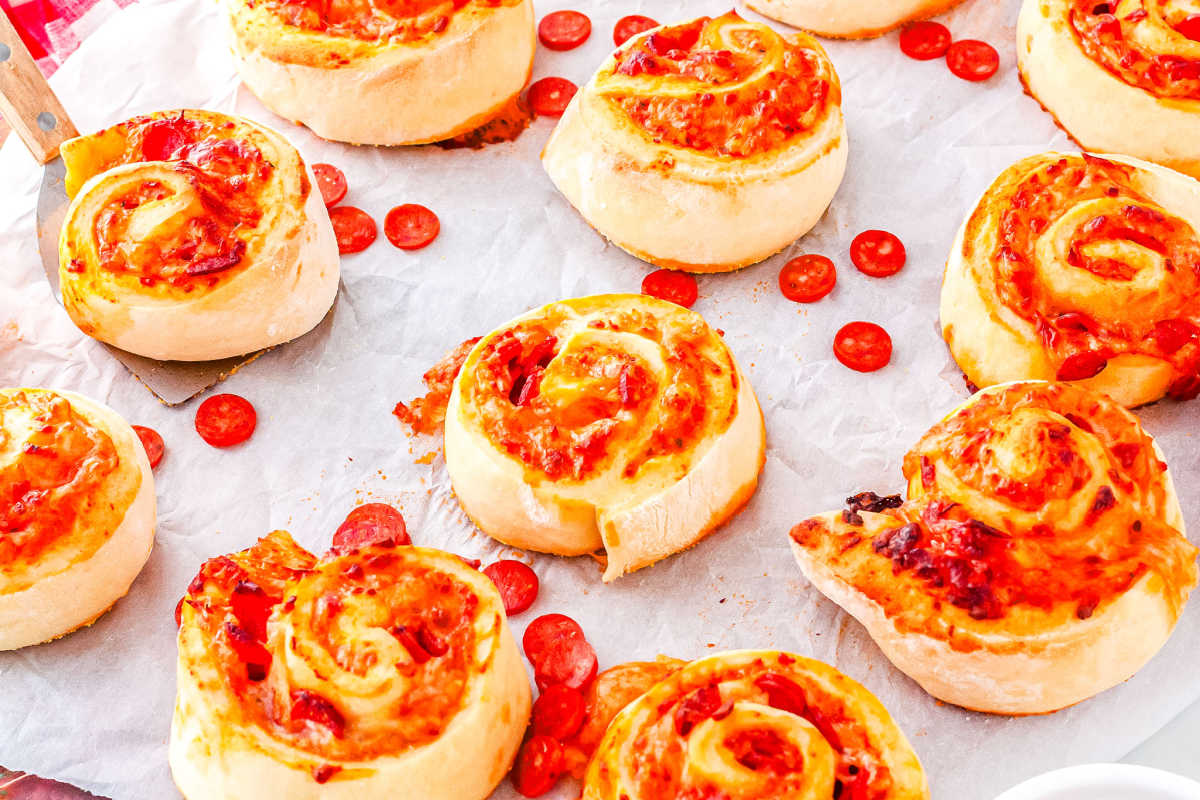 a tray of pepperoni pizza rolls with pepperoni slices scattered throughout the tray