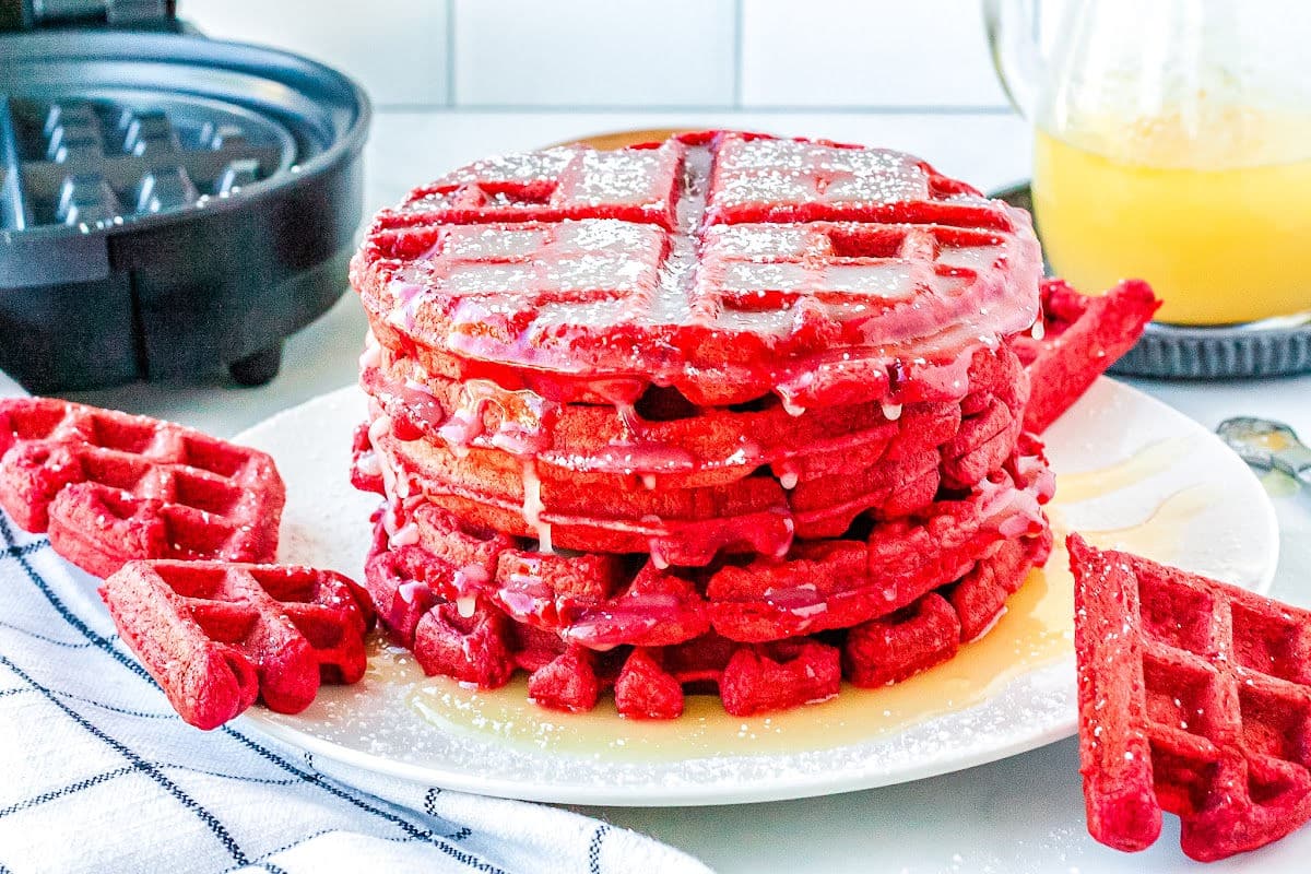 a stack of red velvet waffles on a plate with buttermilk syrup