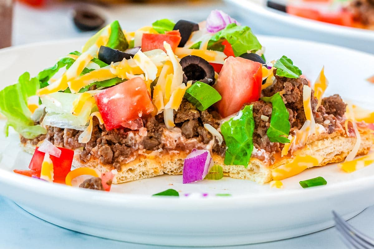 A slice of the finished Taco Pizza recipe on a white plate and cut into.