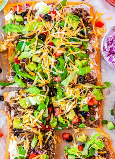 The finished taco pizza with crescent rolls on a wooden cutting board.