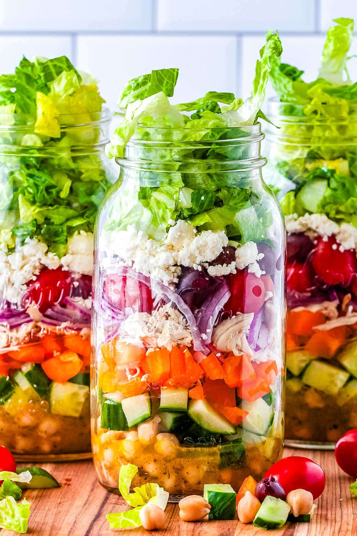 Three Mason Jar Greek Salads on a counter top. 