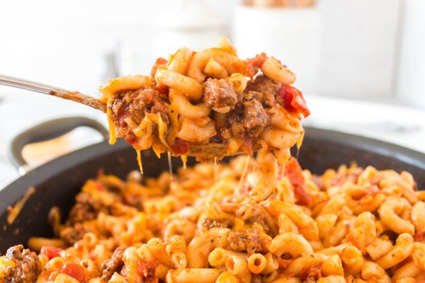 A spoon picking up a heap of American Goulash with cheese pulls trailing behind it.