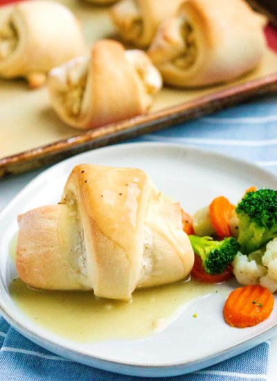 Chicken pillow on a white plate with steamed vegetables.