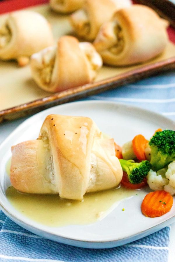 Chicken pillow on a white plate with steamed vegetables. 