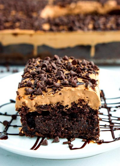 A slice of cake on a white plate with chocolate drizzle.