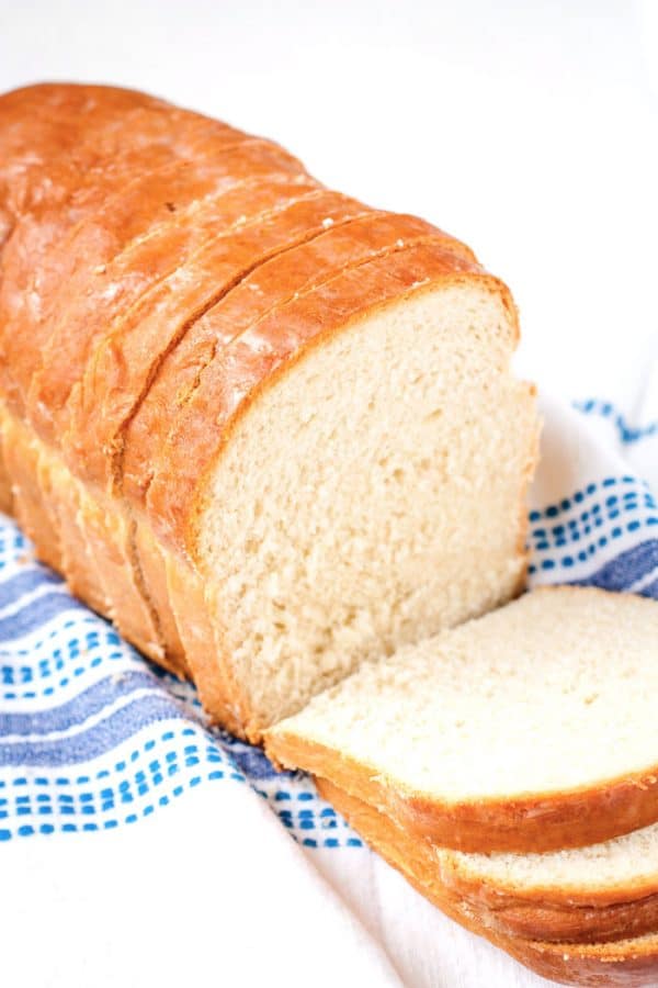 A homemade white bread loaf cut into slices.