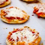Close up of English muffins pizzas on a baking sheet.
