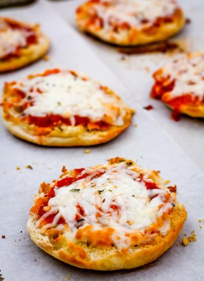 Close up of English muffins pizzas on a baking sheet.
