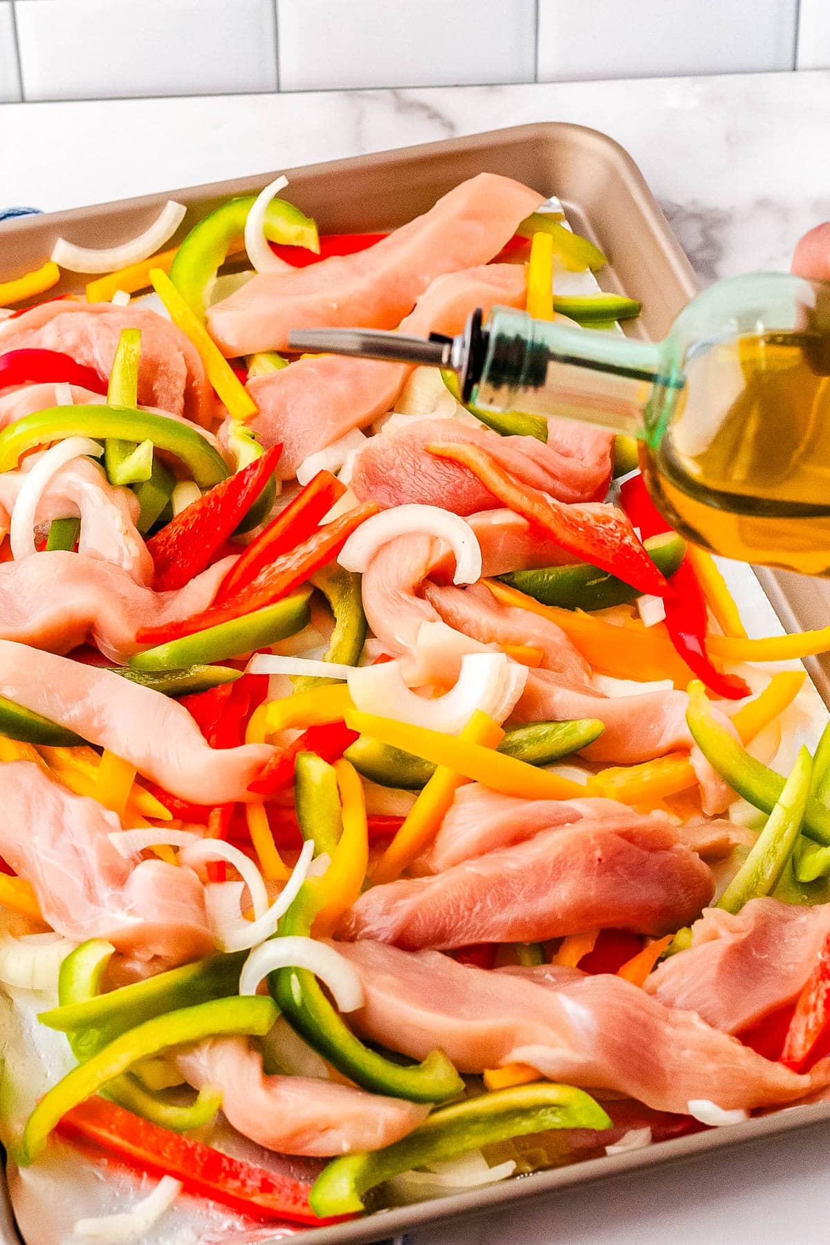 Olive oil being drizzled over the fajita mix.
