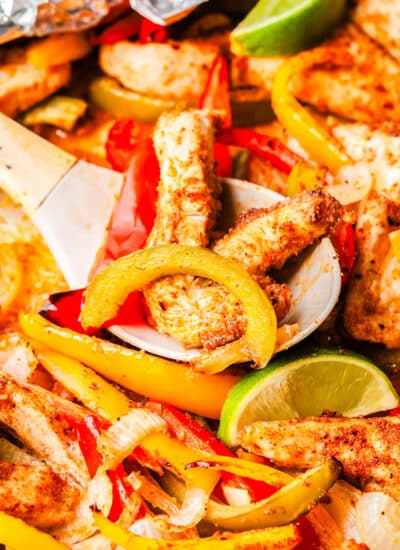 A wooden spoon scooping up some Sheet Pan Fajitas.
