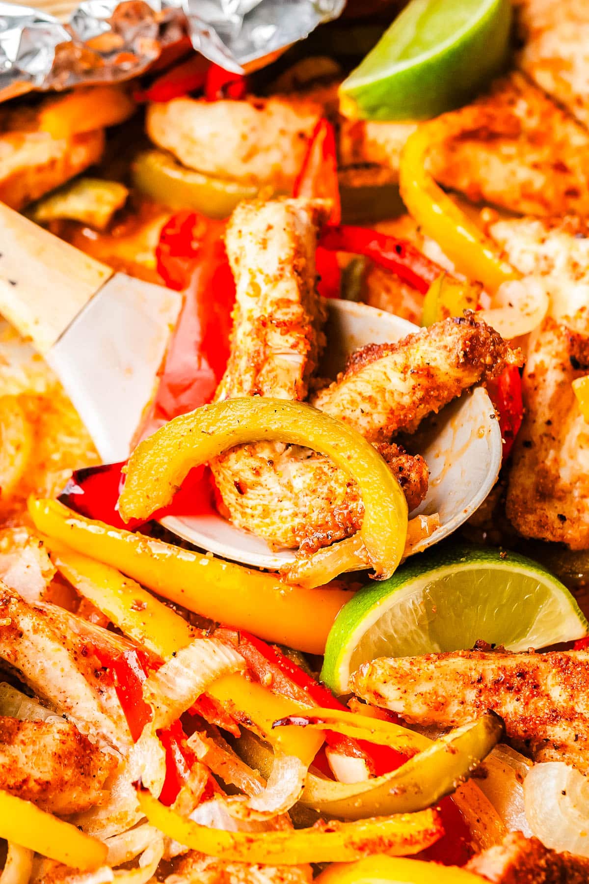 A wooden spoon scooping up some Sheet Pan Fajitas.