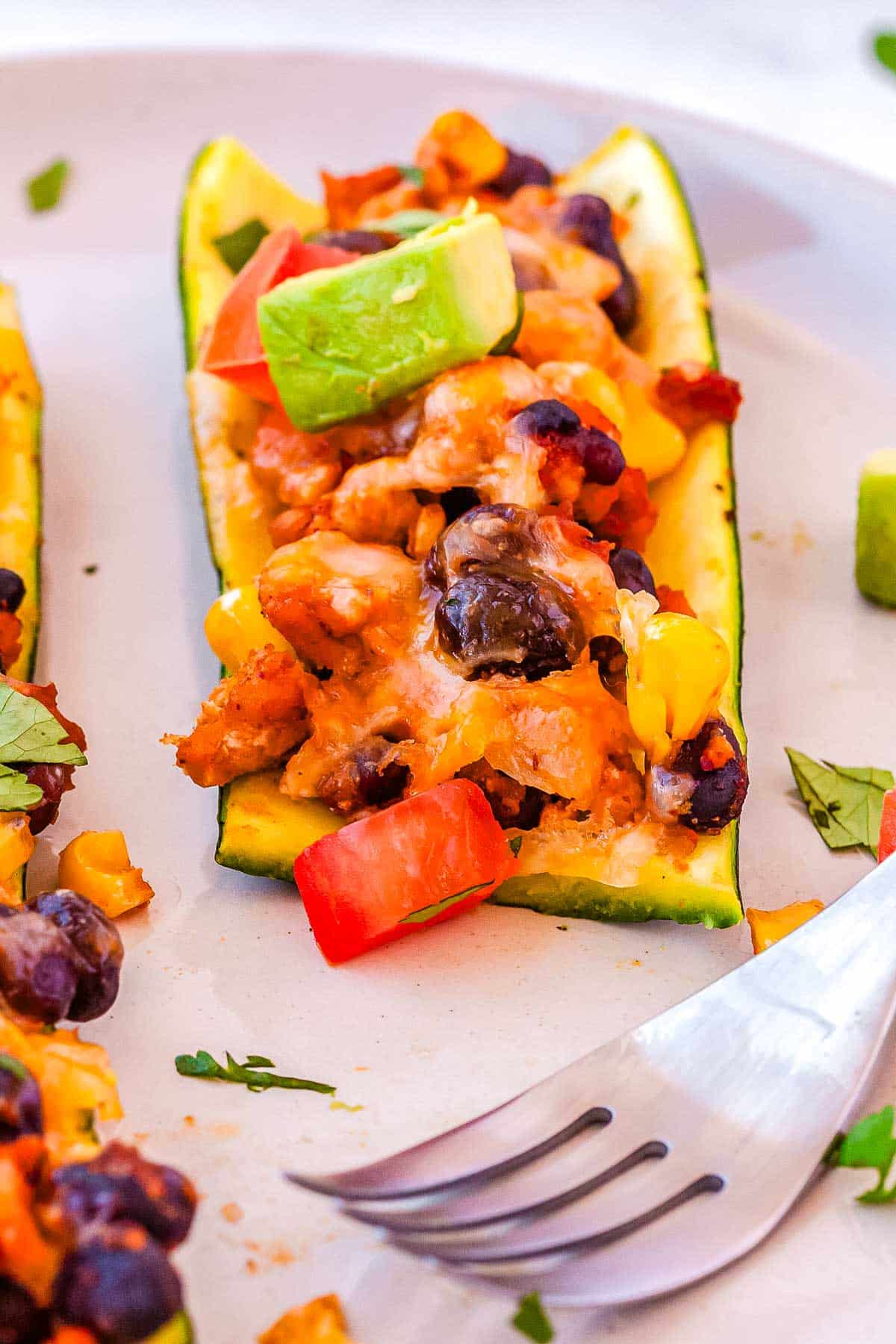 A fork digging into one of the fnished zucchini taco boats.