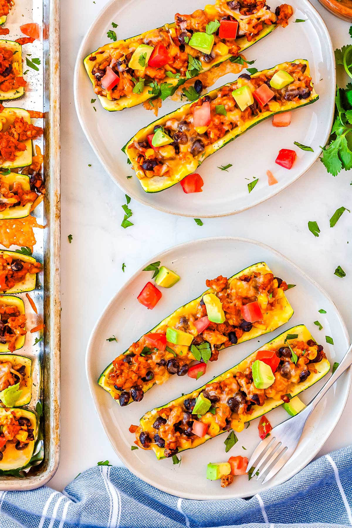 A few of the finished taco zucchini boats on white plates.